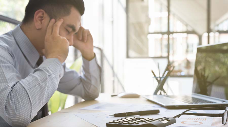 frustrated man sitting by paper laptop table